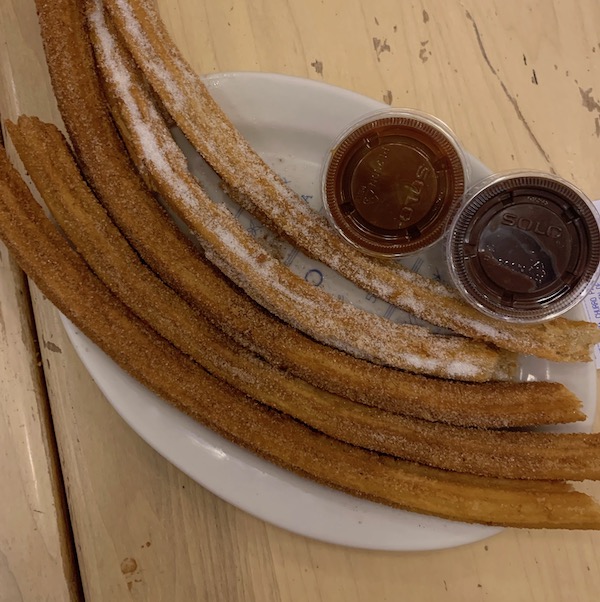 Five pieces of fresh churros with side dipping sauces of caramel and chocolate