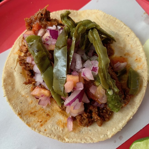 A mixiote taco filled with red onion and pineapple salsa, and stewed cactus paddles