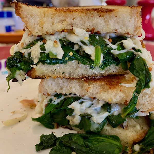 a grilled cheese sandwich with wilted spinach, whole grain mustard, and melted mozzarella on buttered bread